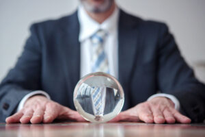 Business person sitting in front of a crystal ball predicting 2024 trends.