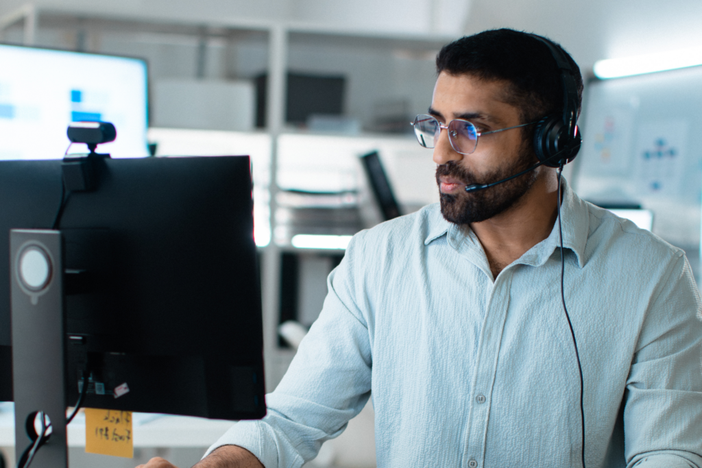 A man working in a call center office helping assist customers.